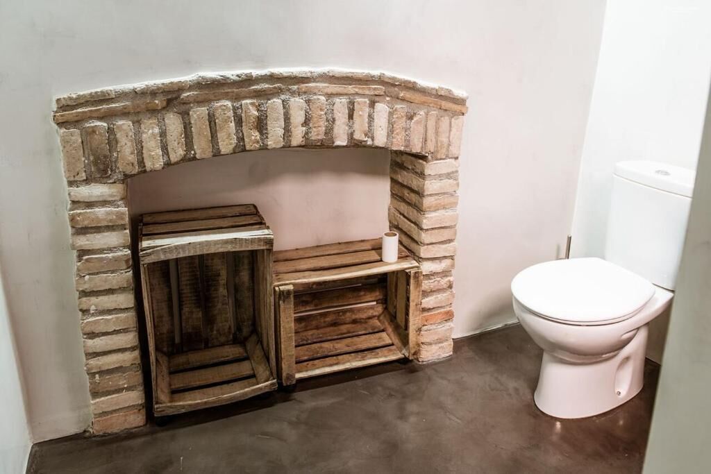 A bathroom with a brick fireplace, wooden bench, and a toilet.