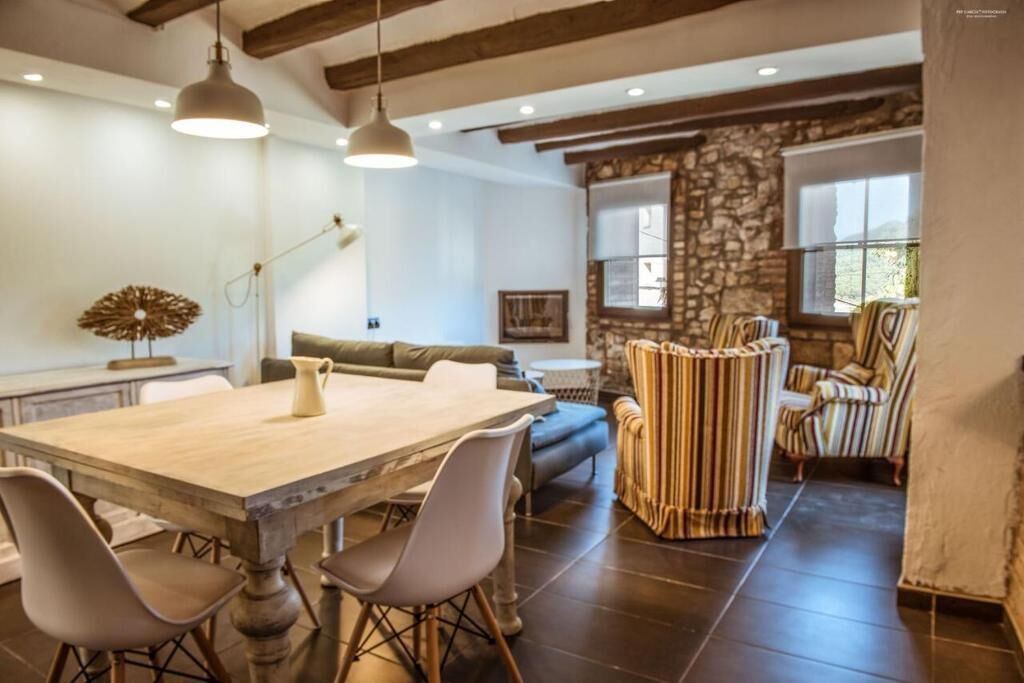 A dining area with a wooden table, chairs, and pendant lights.