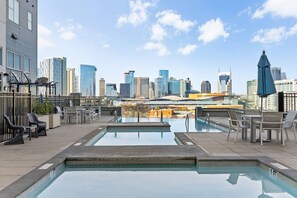 A rooftop pool with a city skyline view, outdoor seating, and a clear sky. - Bach HQ | Walk to Broadway | Arcade + Pool (Nashville)