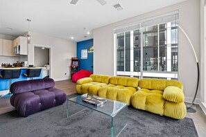 Ein modernes Wohnzimmer mit einem Glastisch, einem violetten Sofa und einem gelben Sofa.