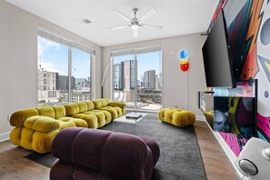 A modern living room with a large sofa set, a coffee table, and a television. - Bach HQ | Walk to Broadway | Arcade + Pool (Nashville)