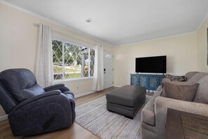 A living room with a reclining chair, a sofa, a flat-screen TV, and a decorative cabinet. - Near downtown, ETSU & VA · Pet-Friendly 1BR (Johnson City)