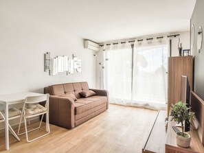 A modern living room with a sofa, a dining table, and chairs. - Apartment with terrace and garage in St-Laurent (Saint-Laurent-du-Var)