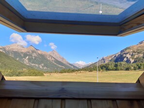 Ein Zimmer mit Oberlicht, Holzboden und Blick auf Berge.