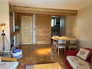 Ein gemütlicher Raum mit Holzboden, einem Esstisch mit Stühlen, einem roten Sofa und einem Globus auf einem Regal.