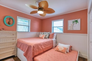 Ein Schlafzimmer mit zwei Betten, einem Deckenventilator, einer Kommode und einem Fenster mit Jalousien.