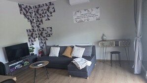 A modern living room with a sofa, TV, and a wall with geometric patterns. - Vacation Home Rose (Kutjevo)
