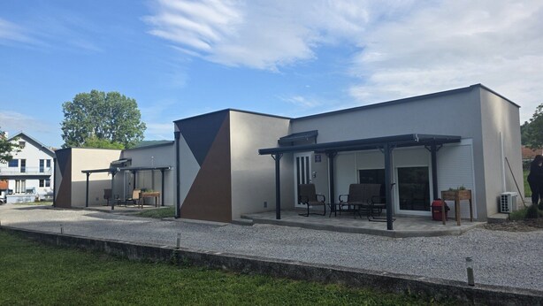 A modern building with a covered patio area, outdoor seating, and a gravel driveway. - Vacation Home Rose (Kutjevo)