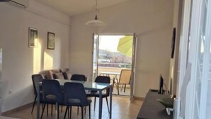 A modern kitchen with a dining area, a large window, and a view of the outdoors. - Apartments Ordulj (Rogoznica)