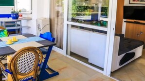 Um espaço compacto com área de jantar, cozinha compacta, varanda com vista e televisão.
