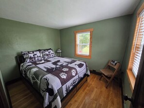 Ein Schlafzimmer mit Bett, Fenster, Stuhl und Tür.