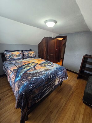A bedroom with a bed, wooden wardrobe, and a ceiling light.