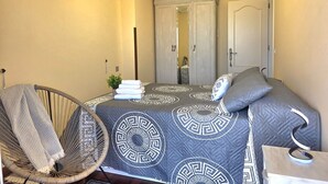 A bedroom with a bed, a chair, a mirror, and a door. - Apartment Ora al Mare - 32002 (Pedreña)