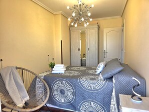 A bedroom with a bed, a chair, a mirror, and a door. - Apartment Ora al Mare - 32002 (Pedreña)