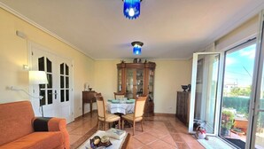 A living room with a sofa, dining table, chairs, a cabinet, and a view through a sliding glass door. - Apartment Ora al Mare - 32002 (Pedreña)