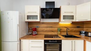 Eine kleine Küche mit Kühlschrank, Mikrowelle, Herd, Backofen und Spüle.