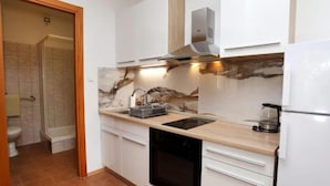 Une cuisine compacte équipée d’un lave-vaisselle, d’un four et d’une plaque de cuisson intégrée.