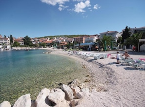 A beach with clear water, a sandy shore, and buildings in the background. - Apartments Gogi (Okrug)
