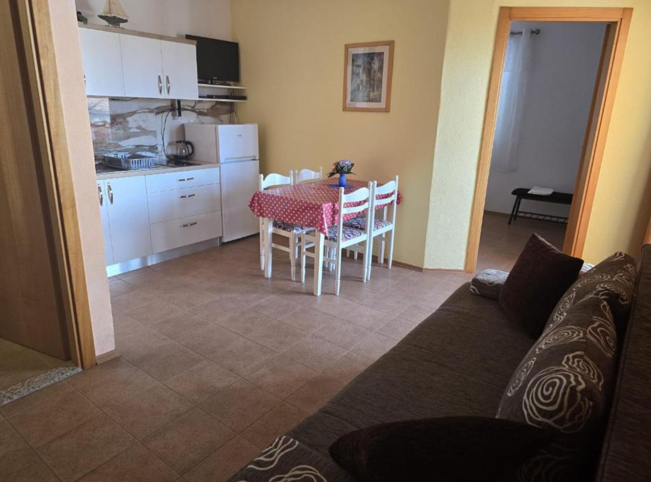 A compact living space with a kitchenette, a dining area with a table and chairs, and a sofa.