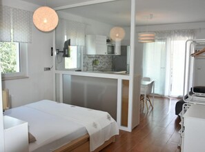 Ein Schlafzimmer mit Bett, einer Küchenzeile, einem Essbereich und einem Badezimmer.