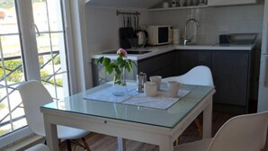 A modern kitchen with a glass table, white chairs, and a view through large windows. - Apartments Near the Beach Orebic (Orebic)
