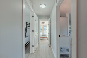 A hallway with a bed at the end, a closet, and a door leading to another room. - Steps to beach, water views. 4-bedroom, 2-bathroom house, sleeps 8. (Lower Township)