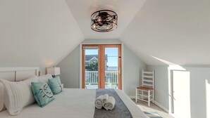 Ein Schlafzimmer mit Bett, Kissen, Handtuch, Stuhl, Balkon und Blick ins Freie.