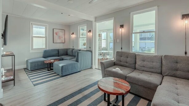 Ein modernes Wohnzimmer mit einem Ecksofa, einem runden Couchtisch und einem Deckenventilator.