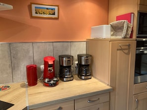 A kitchen with a coffee maker, a red kettle, and a framed picture on the wall. - Large Family Home in Normandy (Ganzeville)