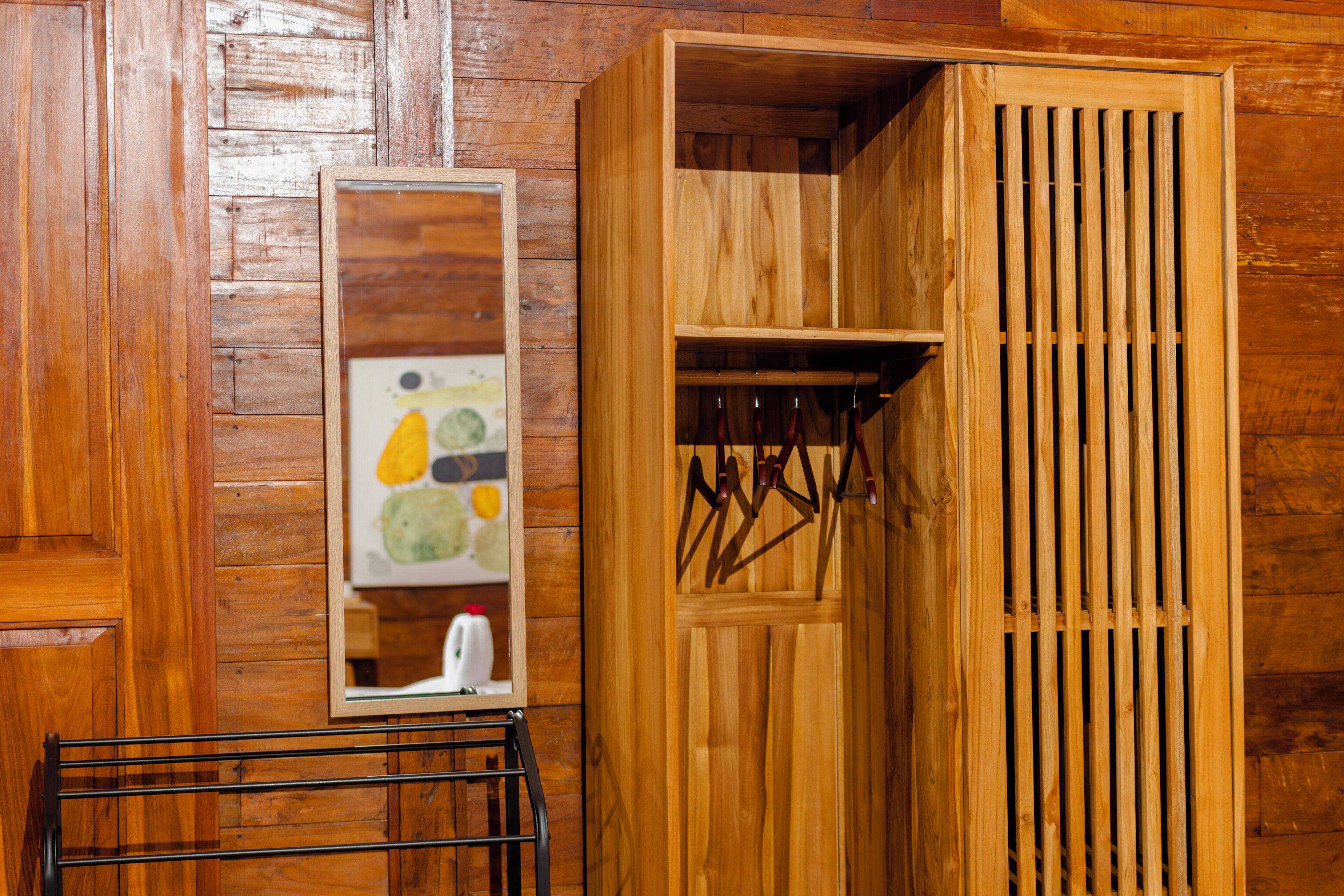 Een houten garderobe met spiegel en kledingroede.