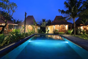 A swimming pool with a view of overwater bungalows at dusk. - Laksmi Viridis Villas (Gianyar)