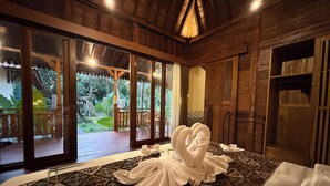 Una habitación con una cama grande, paredes de madera y vista a un jardín.