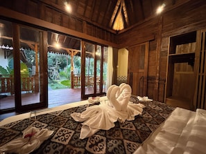 A room with a large bed, wooden walls, and a view of a garden. - Laksmi Viridis Villas (Gianyar)