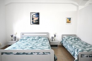 Ein Schlafzimmer mit zwei Einzelbetten, einem Nachttisch mit Lampe und einem gerahmten Bild an der Wand.