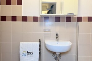 Ein Badezimmer mit einem weißen Waschbecken, einem Handtuch mit einem Logo und einem Spiegel über dem Waschbecken.
