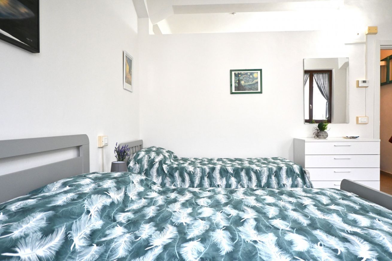 A bedroom with a bed, a dresser, a mirror, and a framed picture on the wall.
