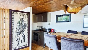 Eine moderne Küche mit Edelstahlgeräten, ein Essbereich mit Holztisch und Stühlen sowie ein dekoratives Wandbild.