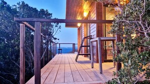 A wooden deck with a view of the sea, a wooden railing, and a table. - La Caouanne Lodges: Panoramic sea view at the Île du Levant naturist resort (Hyères)