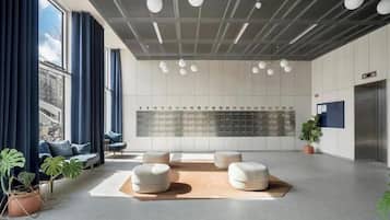 En moderne lobby med siddeområde, vægmonteret skabsystem og en potteplante.