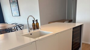 Una cocina moderna con encimera blanca, lavamanos integrado y suelo de madera.