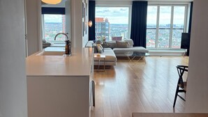 Un apartamento moderno con cocina, comedor y sala de estar, con un amplio ventanal que ofrece vistas a la ciudad.