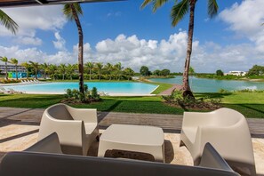A poolside area with lounge chairs and a view of a large pool and beach. - 2 bedrooms, swimming pools, hot tub, gym (Punta Cana)