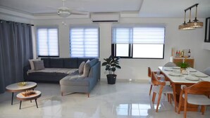 Ein modernes Wohnzimmer mit einer Couch, einem Esstisch, Stühlen und einer Chandelier.