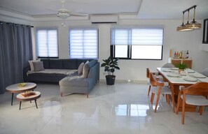 A modern living room with a sofa, dining table, chairs, and a chandelier. - Lux 2-Story 3BR Villa + Private Pool (Punta Cana)