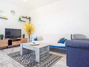 Een woonkamer met een flatscreen televisie, een salontafel, een bank en een decoratieve plant.
