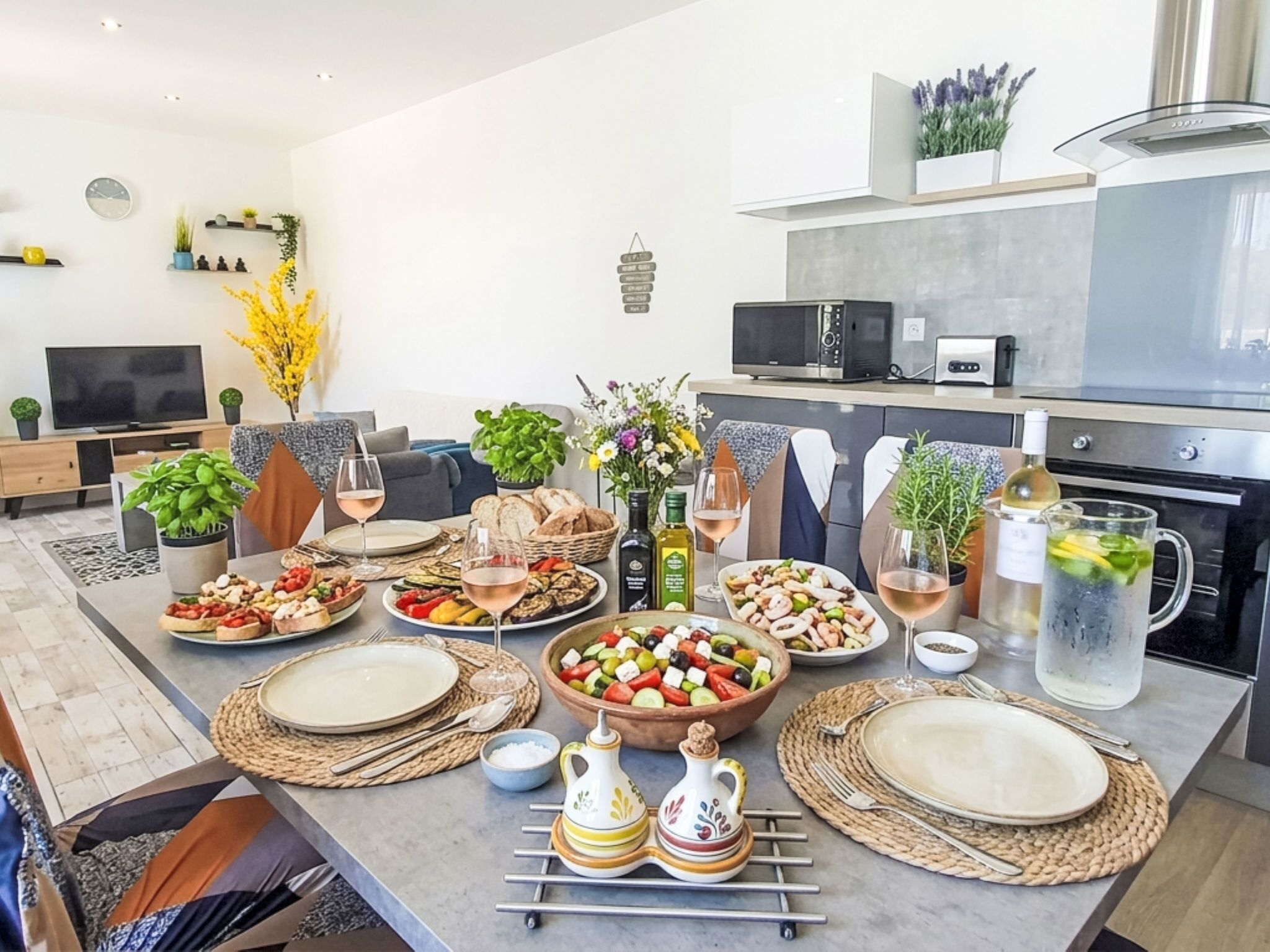 A modern kitchen with a dining area, equipped with a microwave, oven, and a variety of food items on the counter.