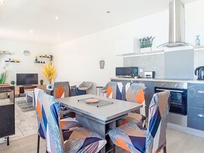Een moderne keuken met een magnetron, waterkoker en oven. Er is een eethoek met een tafel en stoelen.