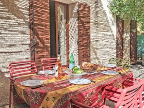 An outdoor dining area with a table set for two, featuring a red tablecloth, red chairs, and a basket of bread. - Villa le Cédre 17 by Interhome (Six Fours)