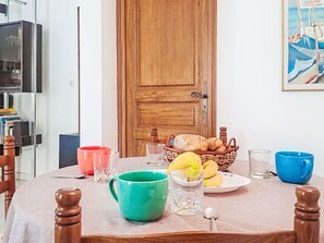 A dining table with a variety of food items and drinks, a wooden door, and a painting on the wall. - Villa le Cédre 17 by Interhome (Six Fours)