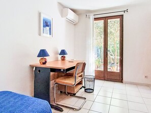 A room with a desk, two lamps, a chair, a bed, and a window with a view of greenery. - Villa le Cédre 17 by Interhome (Six Fours)